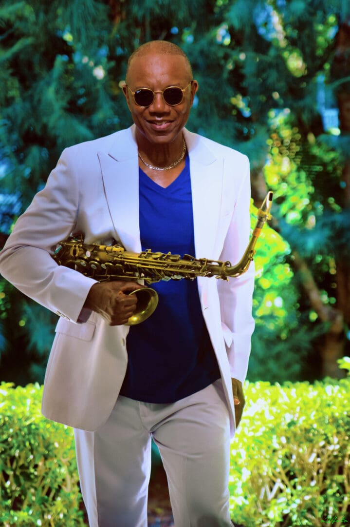 A man in a white suit holding a saxophone.