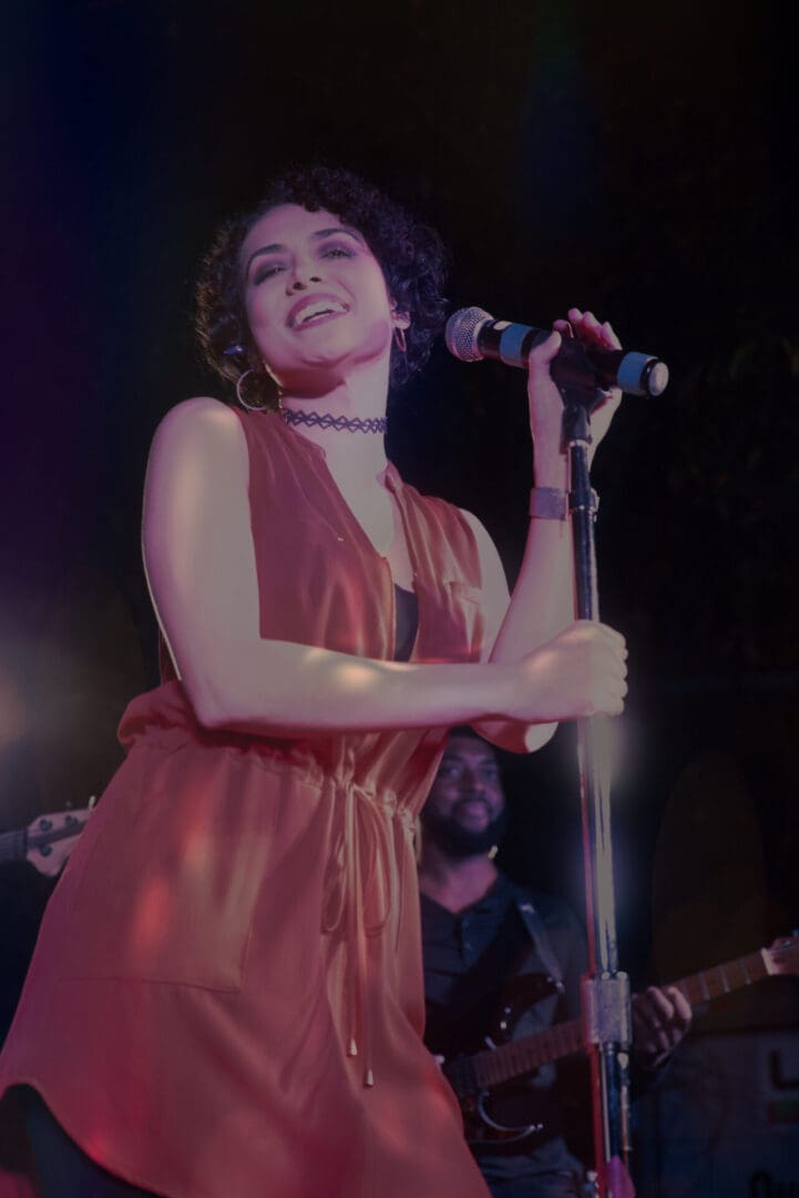 A woman in a red dress singing into a microphone.
